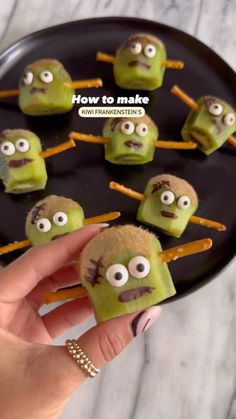 someone is holding up some food made to look like green monster faces with sticks sticking out of them