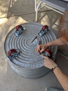 a man is working on an outdoor table made out of tin cans and metal wheels