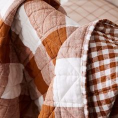 an orange and white checkered comforter on top of a bed next to pillows