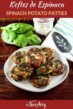 spinach potato patties on a white plate next to basil leaves and a jar of yogurt