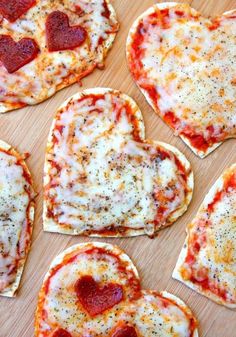 heart shaped pizzas with cheese and pepperoni arranged in the shape of hearts on a cutting board