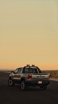 the truck is parked on the side of the road in front of an orange sky