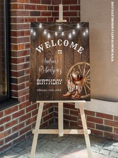 a welcome sign with lights on it in front of a brick wall and door to a building