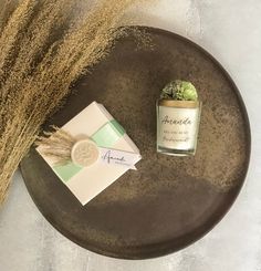 a table with a candle, card and some dried grass on it next to an envelope