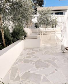 an outdoor living area with white furniture and trees