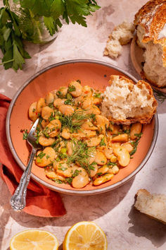 a bowl filled with chickpeas and bread next to sliced lemons on a table