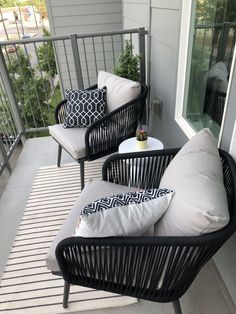 two black wicker chairs sitting on top of a porch