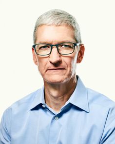 an older man with glasses and a blue shirt is looking at the camera while standing in front of a white background