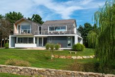 a large house sitting on top of a lush green field next to a tree and grass covered hillside