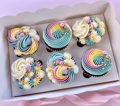 six cupcakes in a box decorated with rainbow icing and flowers on top