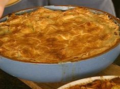 a pie sitting on top of a wooden cutting board next to other food dishes and utensils