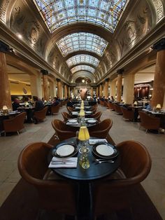 an empty restaurant with tables and chairs in the center, along with skylights overhead