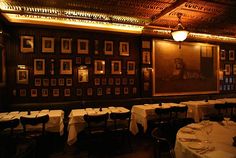 an empty restaurant with tables and chairs in front of a wall full of framed pictures