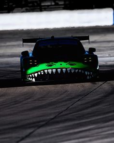 a car with teeth painted on it driving down a race track in the dark at night