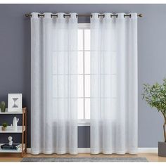 a white curtain hanging on the side of a window next to a potted plant