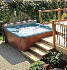 a hot tub sitting on top of a wooden deck next to a small garden area