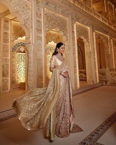 a woman in a white and gold sari is posing for the camera with her hand on her hip