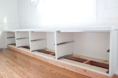 an empty room with white cabinets and wood flooring