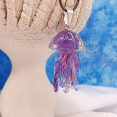 a purple jellyfish necklace is hanging from a white mannequin's head