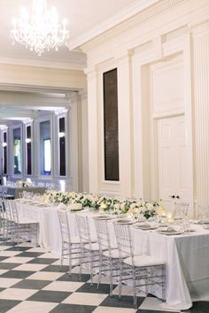 a long table set up with white flowers and place settings for an elegant wedding reception