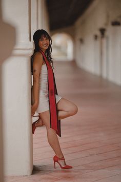 a woman leaning against a pillar with her legs crossed