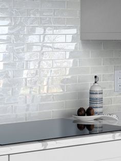 a white kitchen counter top next to a blue and white vase with two apples on it