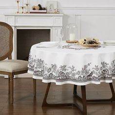 a table with a white table cloth and two chairs in front of a fire place