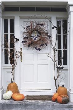 two pumpkins sitting in front of a white door with decorations on the outside and inside