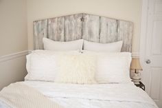 a white bed topped with pillows next to a wooden headboard