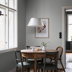 a dining room table with four chairs and a lamp hanging from the ceiling over it