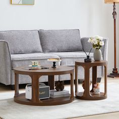 two coffee tables sitting on top of a rug in front of a couch and lamp