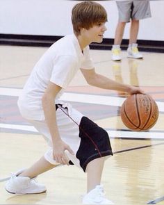 a young boy dribbling a basketball on the court