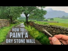 someone is painting a stone wall with green grass and trees