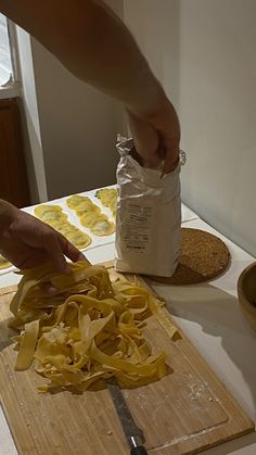 a person cutting up some food on top of a wooden cutting board with a knife