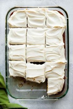 a glass dish filled with white frosting next to a green napkin and some leaves