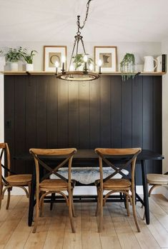 a dining room table with two chairs and some plants on top of the shelf above it