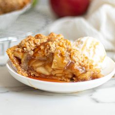 an apple pie on a plate with ice cream and caramel sauce in the background