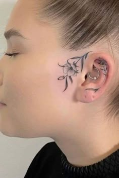 a woman's face with tattoos on her nose and behind the ear is a flower