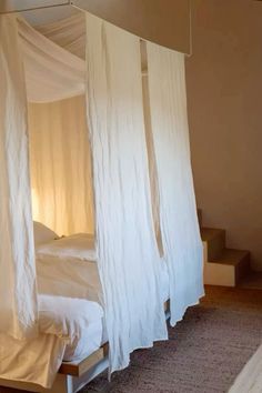 a bed with white drapes hanging from it's sides