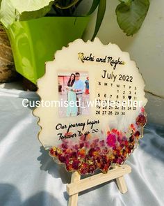 a personalized photo frame with flowers on it and a wooden stand for the calendar