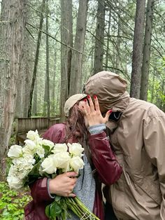 a man and woman kissing in the woods with white flowers on their foreheads,