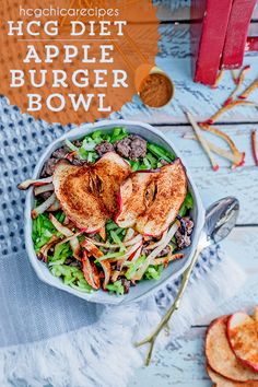 a bowl filled with meat and vegetables on top of a table next to sliced apples