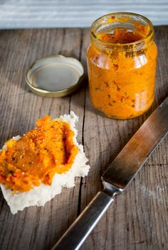 there is a jar of sauce next to a knife and spoon on the table with it