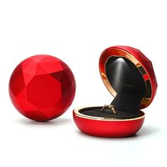 a red box with a black lid next to a shiny red ball on a white background