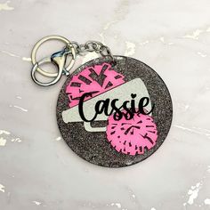 a pink and black keychain with the word casssie on it's side