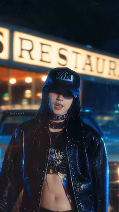 a woman wearing a leather jacket and hat standing in front of a building at night