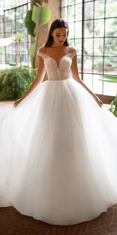 a woman in a white ball gown posing for the camera with her hands on her hips