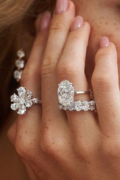 a close up of a person's hand with two rings on their fingers and an engagement ring