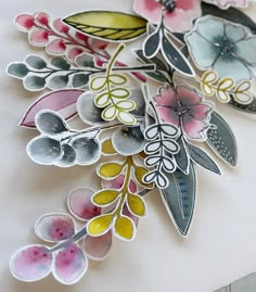 a close up of some paper flowers on a piece of white paper with watercolor paint