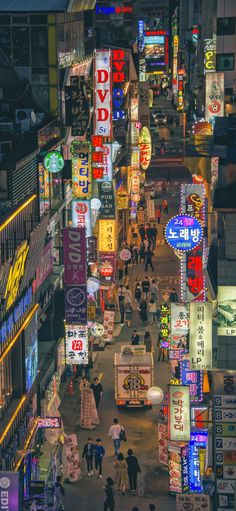 an overhead view of a city street at night with neon signs and people walking on the sidewalk